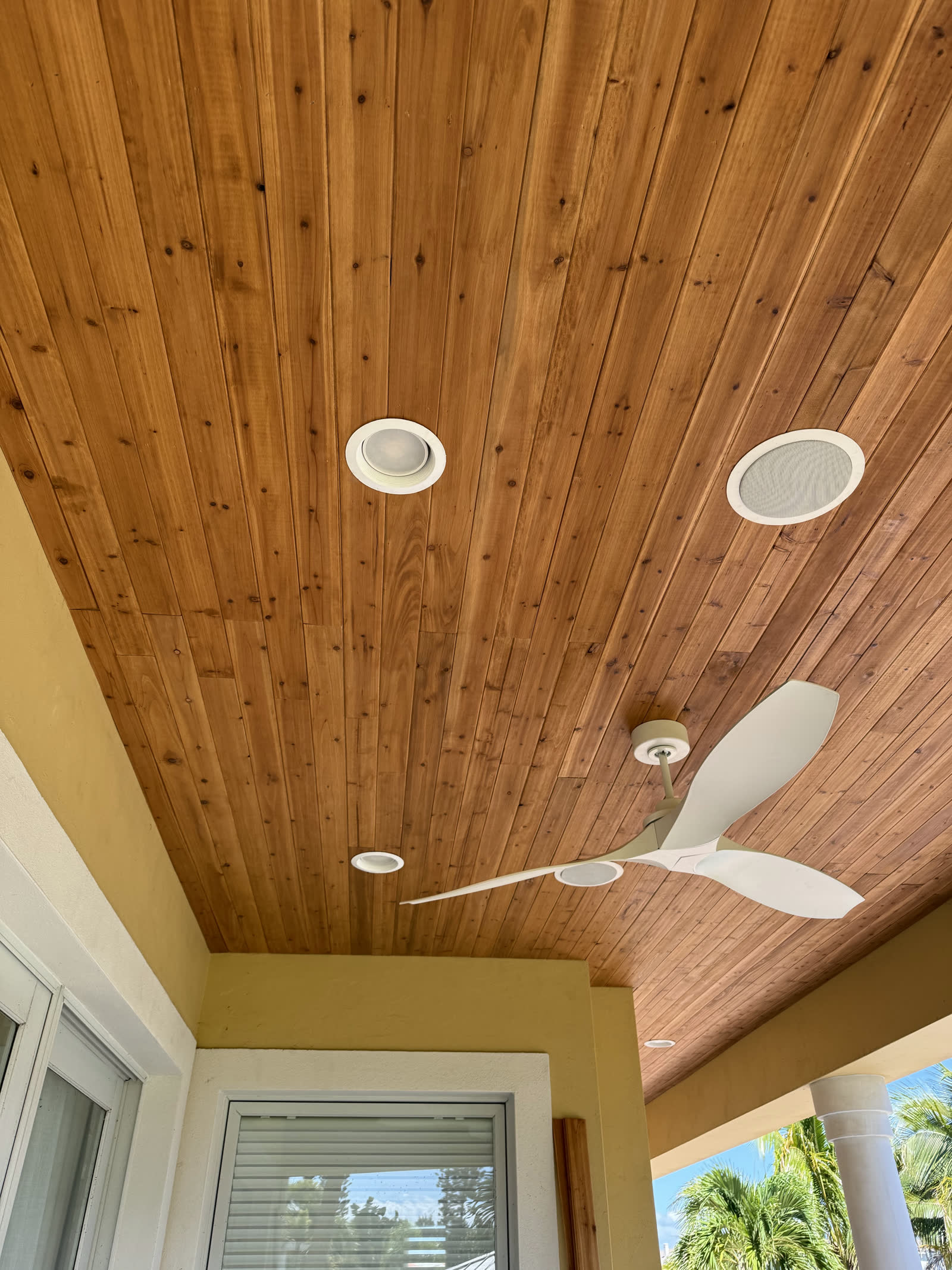 Finished tongue-and-groove wood ceiling on a Florida porch with fan and speakers