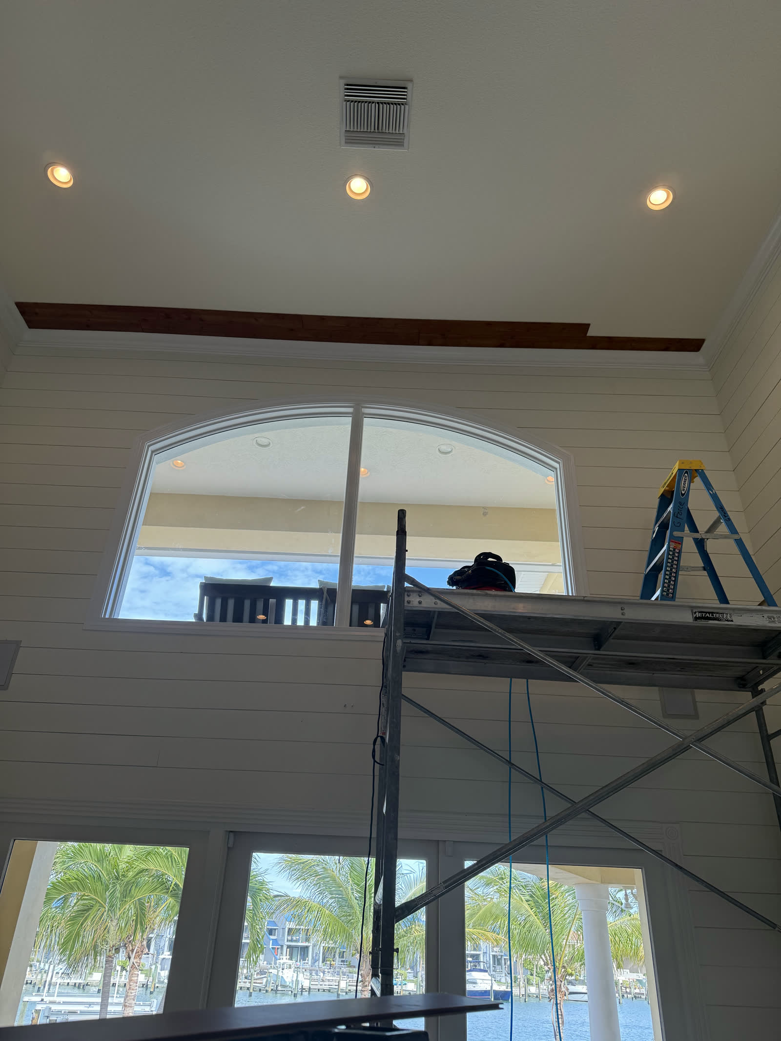Marina-view great room mid-remodel with scaffolding and fresh shiplap walls